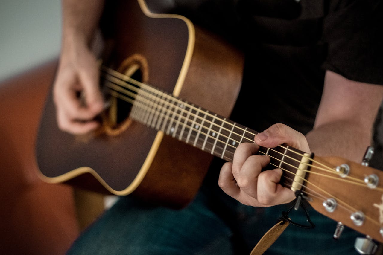 heros-img A musician strums chords on an acoustic guitar, showcasing musical talent.